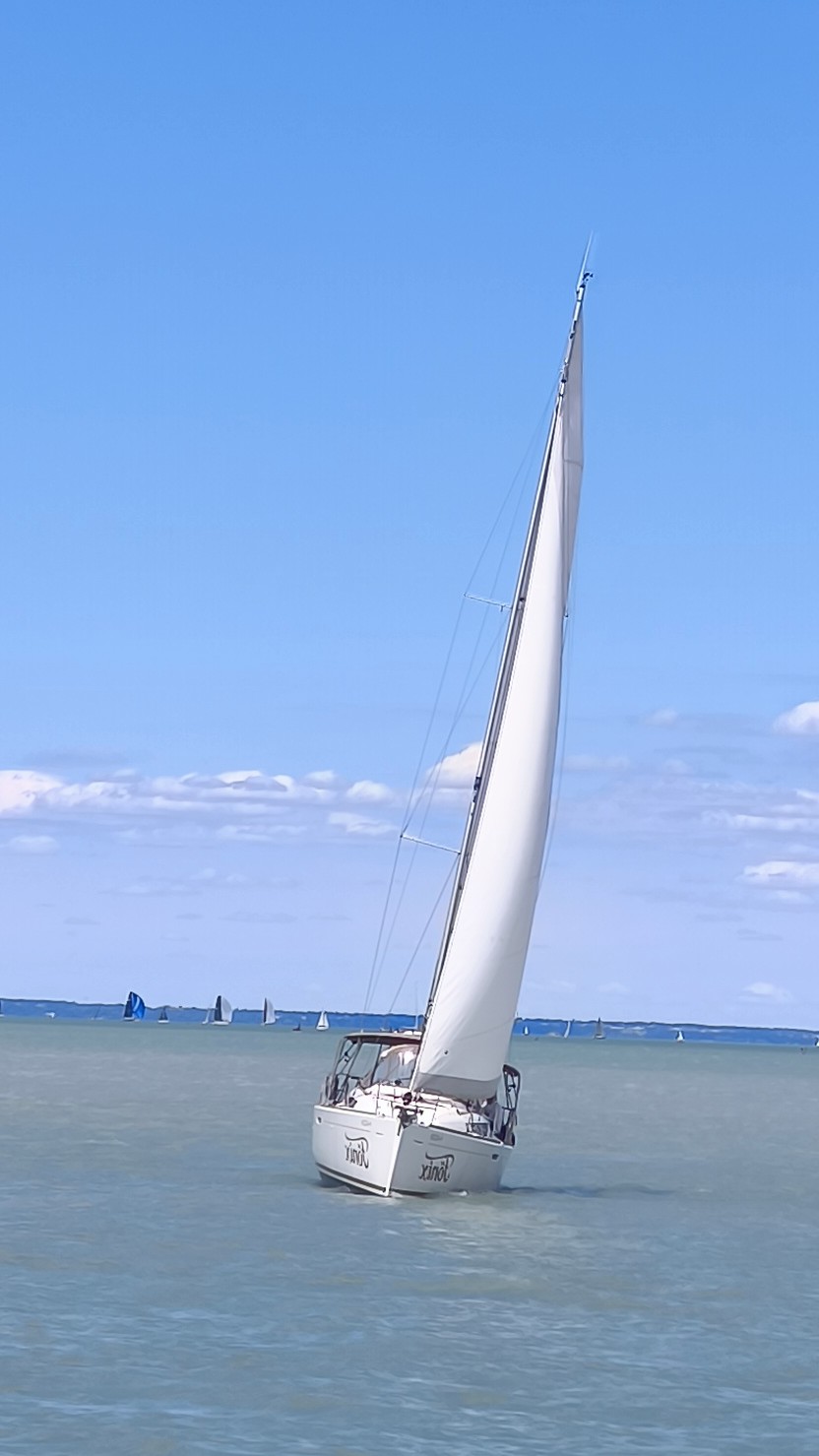 Fehér vitorlás hajó vitorlával a Balatonon, Balatonfüreden vitorlázik.